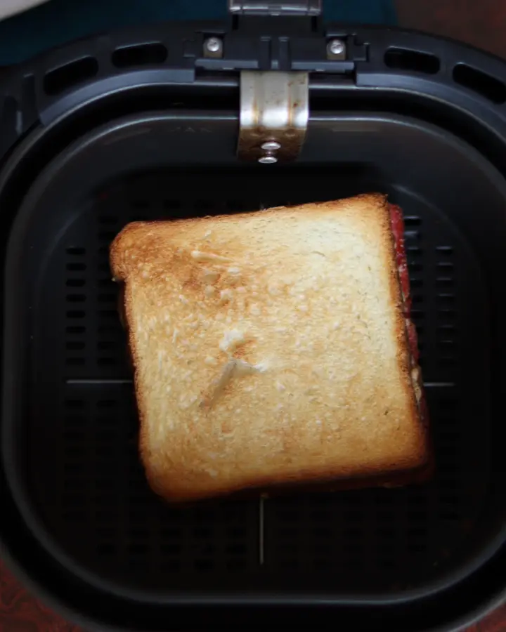 Peanut butter and jelly sandwich cooking in an air fryer basket