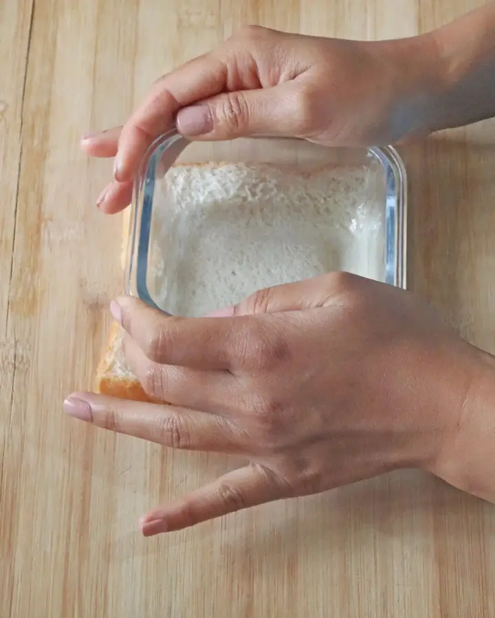 Slice of bread with a pressed well and a cracked egg before air frying