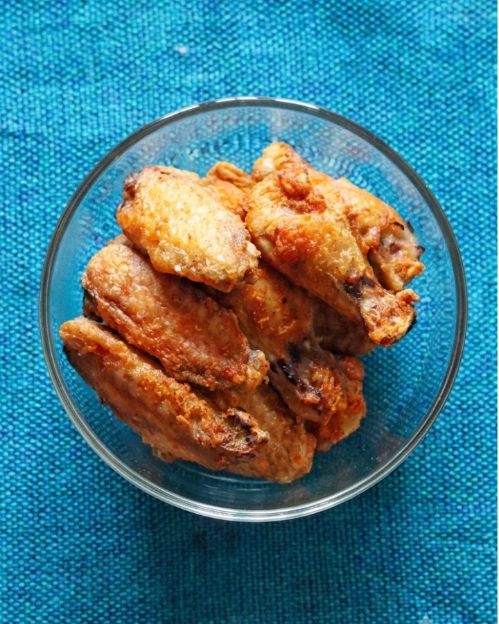 Golden brown frozen chicken wings cooked in an air fryer basket until crispy