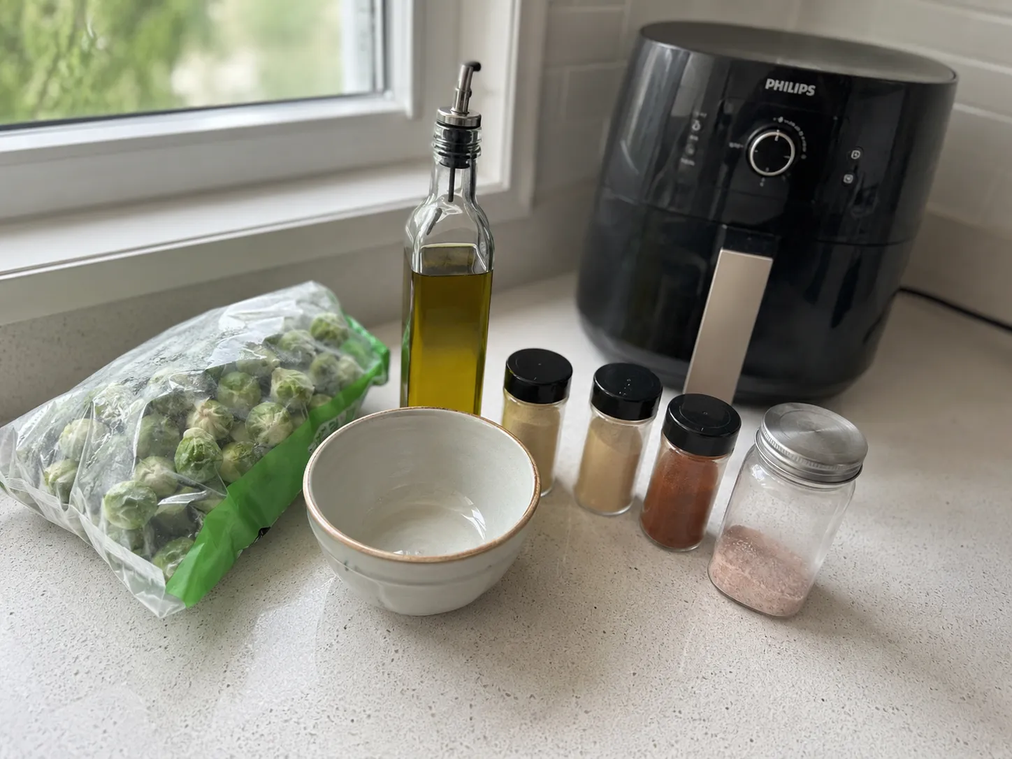 Ingredients for air fryer frozen Brussels sprouts: a bag of frozen sprouts, olive oil, salt, garlic powder, and pepper