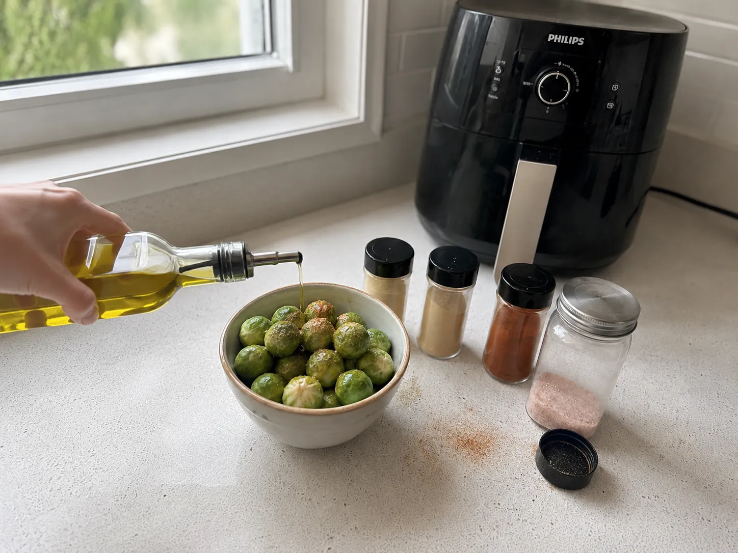 Tossing partially cooked Brussels sprouts with oil and seasonings in a bowl at the halfway point