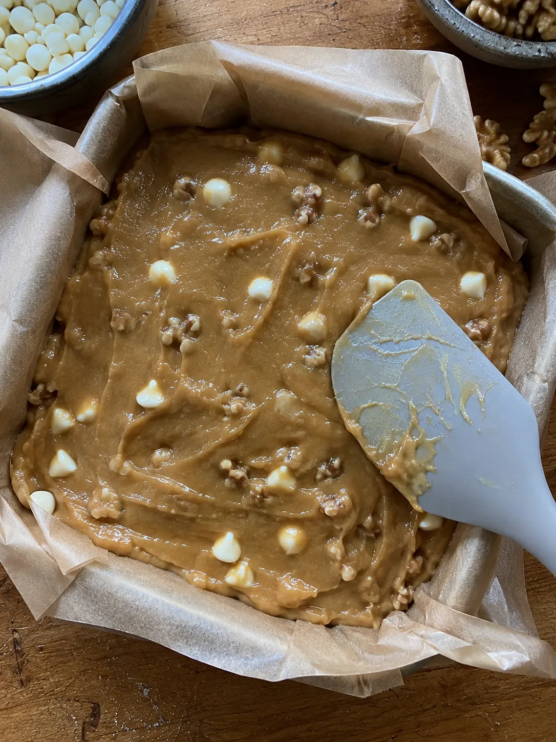Blondie batter spread into a parchment-lined round pan and levelled with a spatula