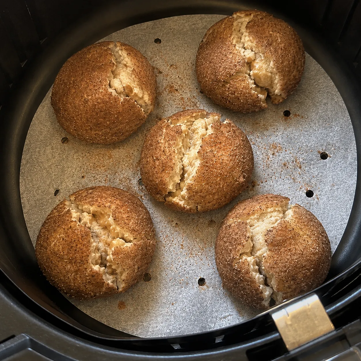 The same five dough balls with their cinnamon sugar shells split open showing pale dough beneath