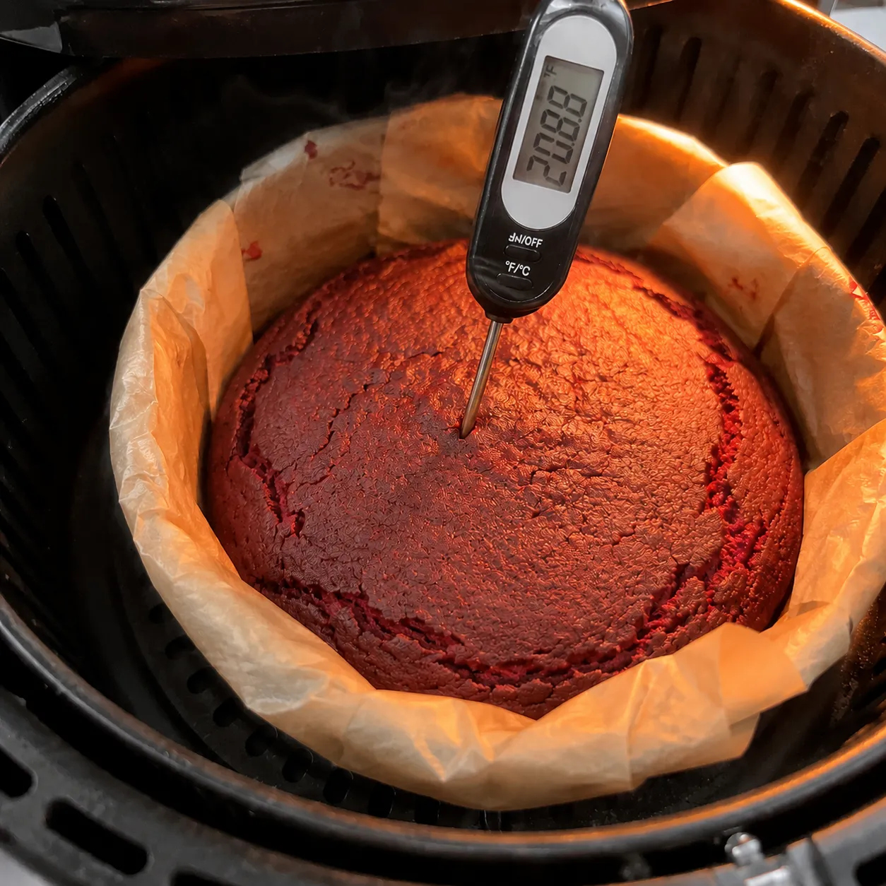 Instant-read thermometer checking the center of an air fryer red velvet cake, reading 208.8 degrees Fahrenheit