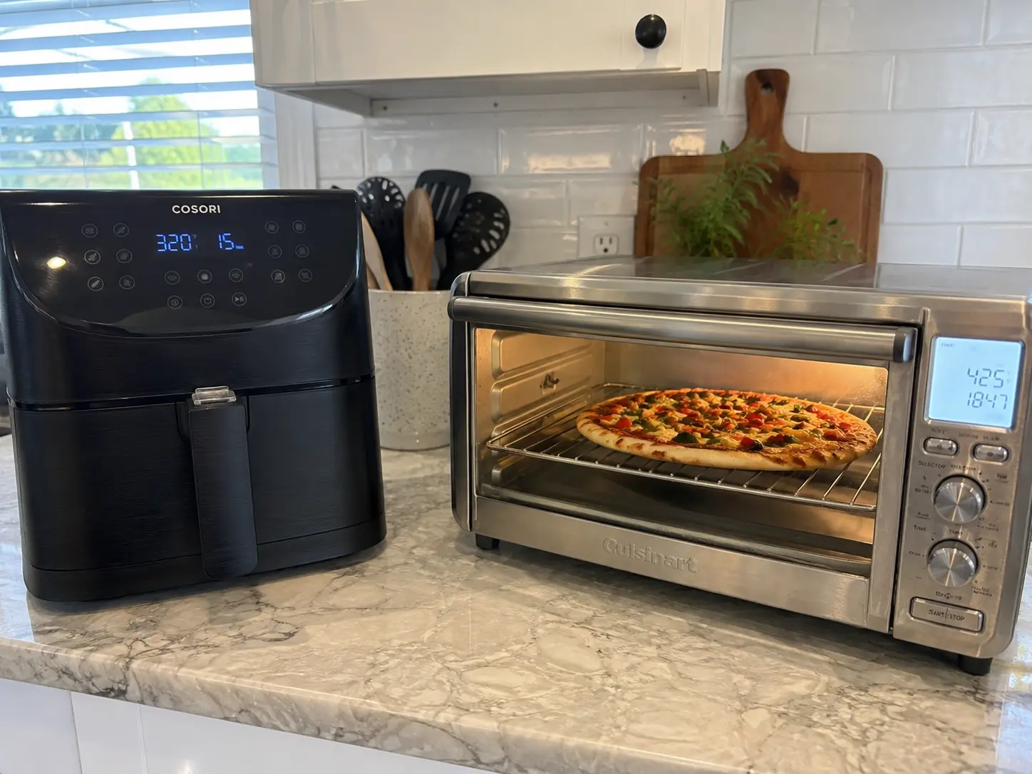 A basket air fryer set to 320F beside a toaster oven baking a pizza on a rack at 425F