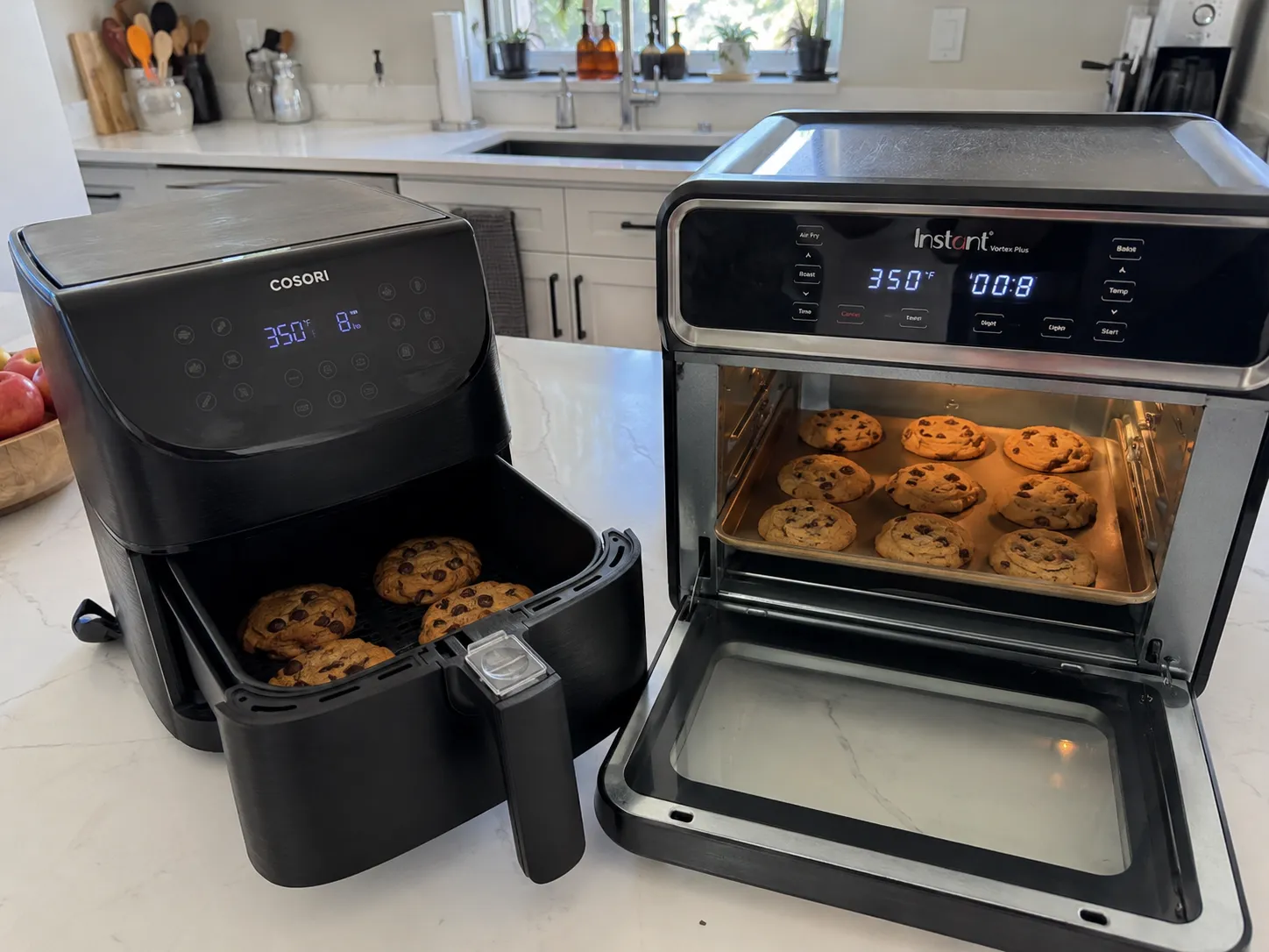 Chocolate chip cookies baking in a Cosori basket air fryer next to two racks of cookies in an Instant oven-style air fryer, both at 350 degrees