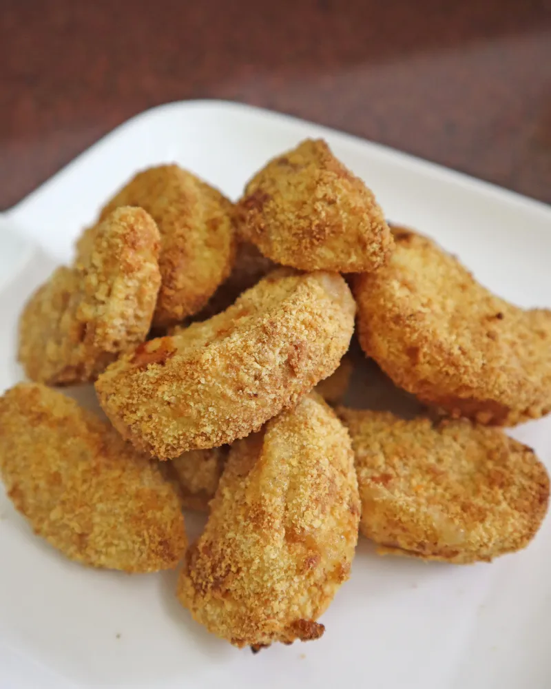 Breaded air fryer apple fries stacked on a white plate