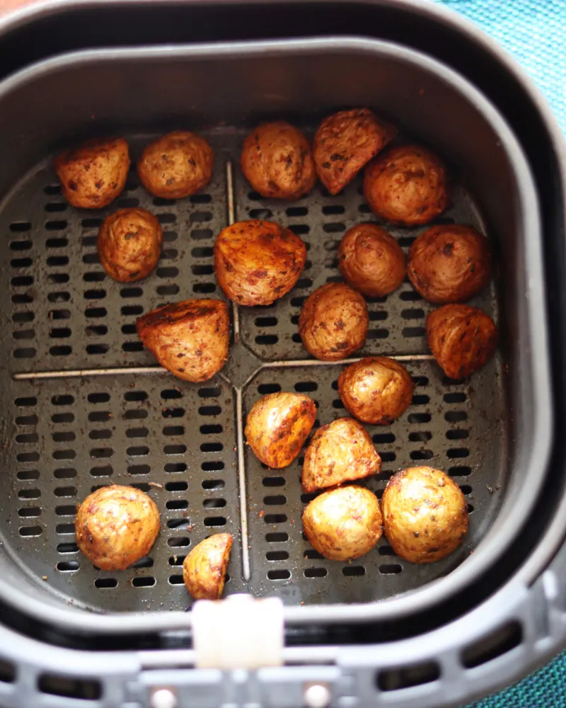 Cut baby potatoes arranged skin side up in a single layer with gaps between them on an air fryer crisper plate
