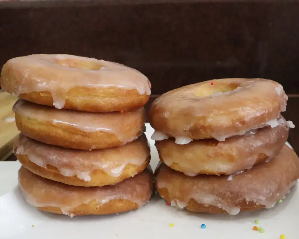Two stacks of glazed vegan air fryer donuts on a white plate, seen from the side