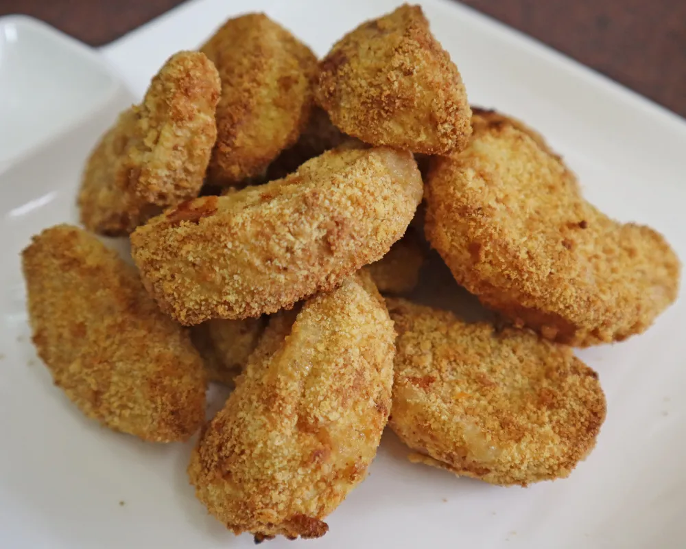 Golden breaded air fryer apple fries piled on a white plate