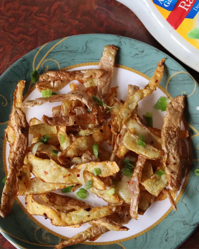 Seasoned crispy potato peels served on a plate beside a bottle of ranch dressing