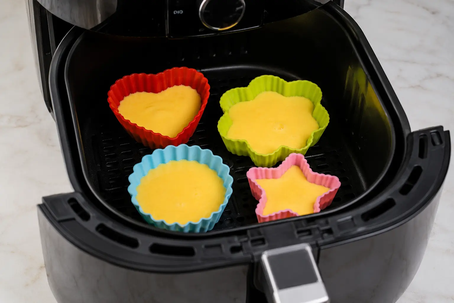 Silicone molds arranged in an air fryer basket with space around each one for airflow