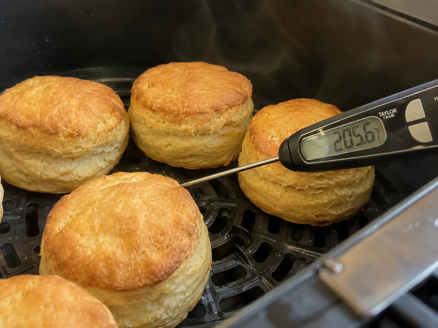 An instant read thermometer in the side of an air fryer biscuit showing 205.6 degrees Fahrenheit