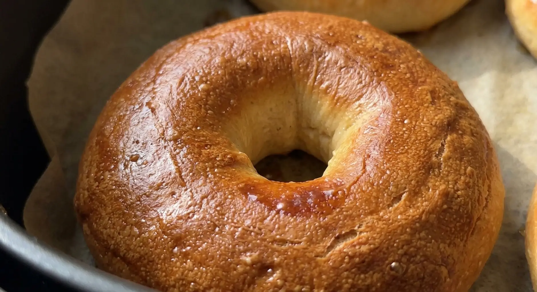 Close view of a baked air fryer bagel with a deep golden glossy crust