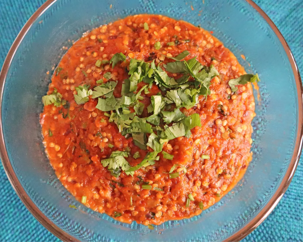 Air fryer baingan bharta in a blue glass bowl topped with fresh cilantro