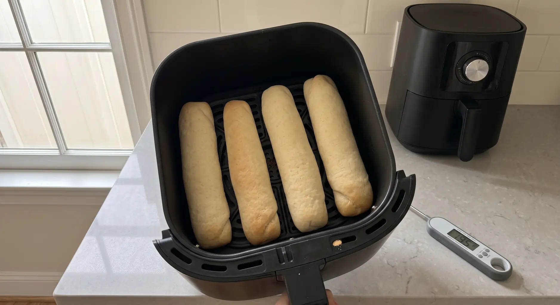 Four pale golden breadsticks spaced apart in an air fryer basket