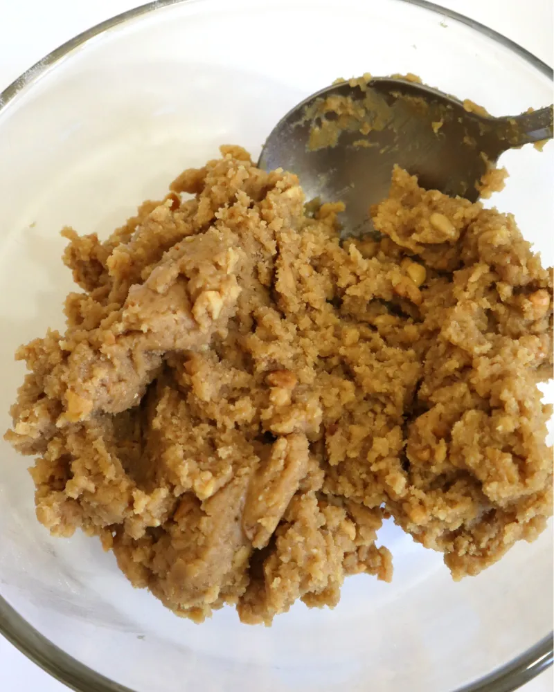 Stiff peanut butter cookie dough mixed in a glass bowl with a spoon