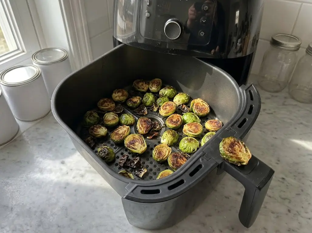 Halved brussels sprouts roasted deep brown in a Philips air fryer basket