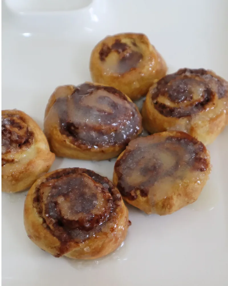 Iced cinnamon rolls arranged on a white plate ready to serve