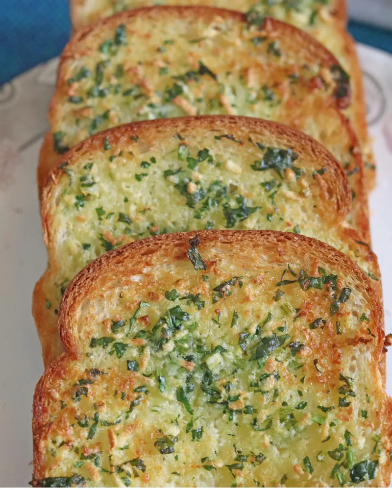 Close-up of crisp air fryer garlic bread slices showing golden garlic flecks and parsley