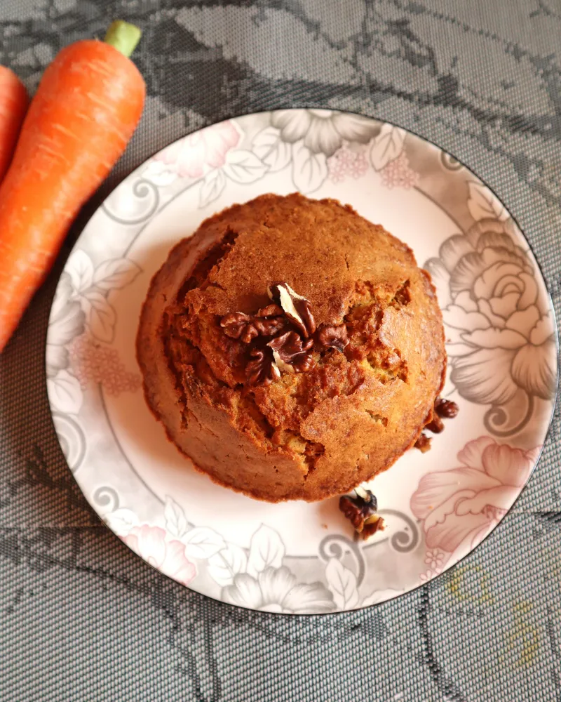 Whole air fryer carrot cake on a plate topped with walnuts, seen from above