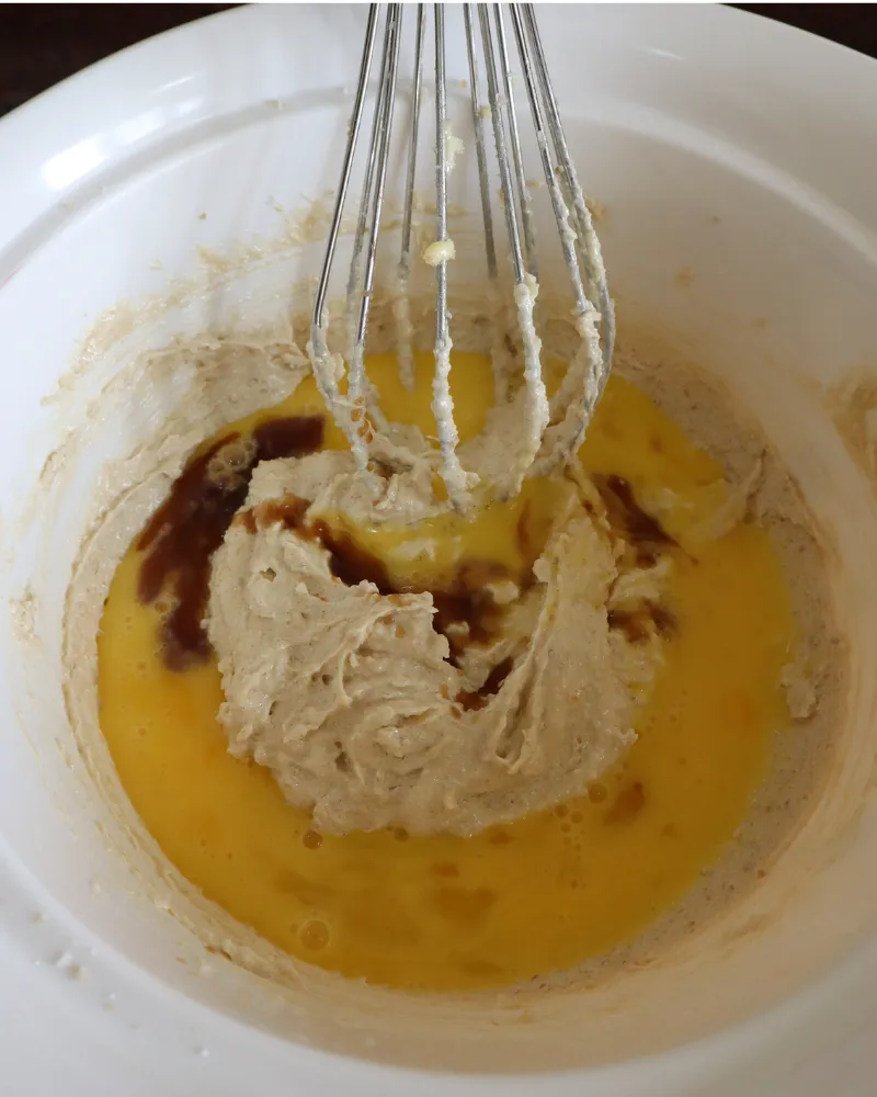 Creamed butter and sugar in a bowl with beaten egg and vanilla being whisked in
