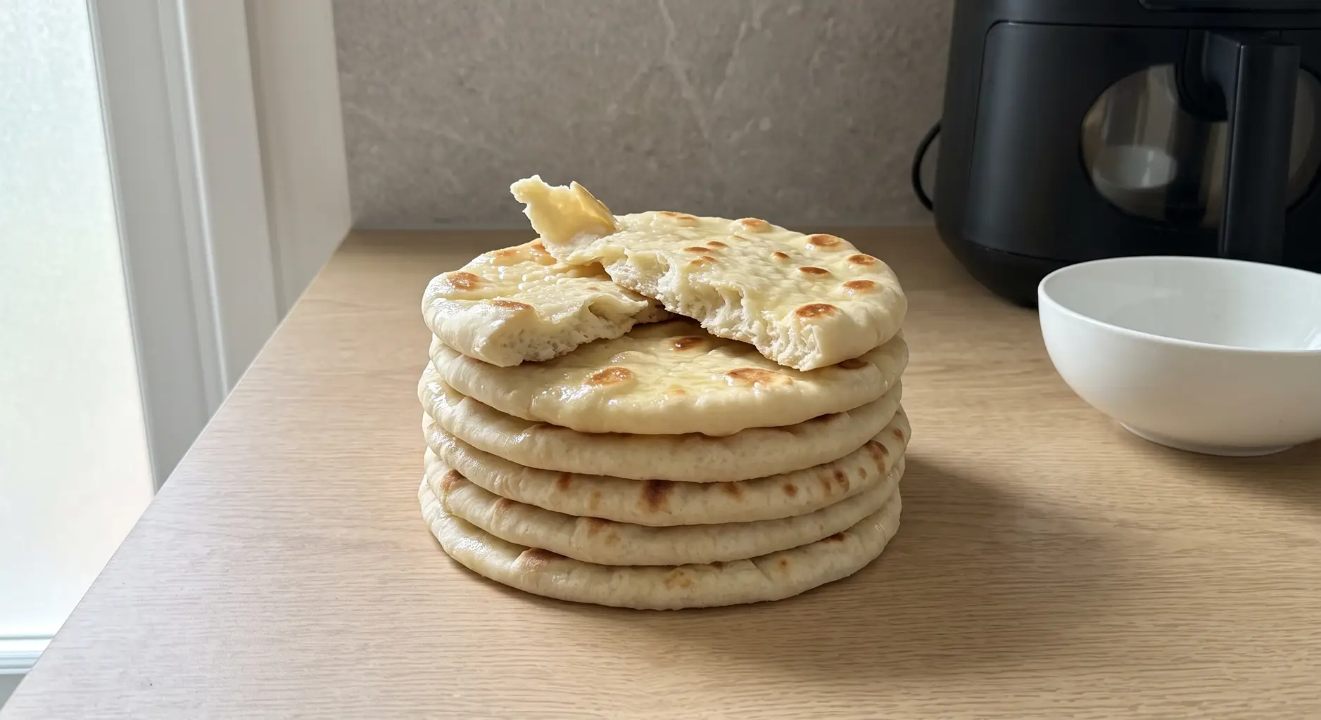 A stack of golden-spotted air fryer flatbreads with the top one folded to show how soft it is