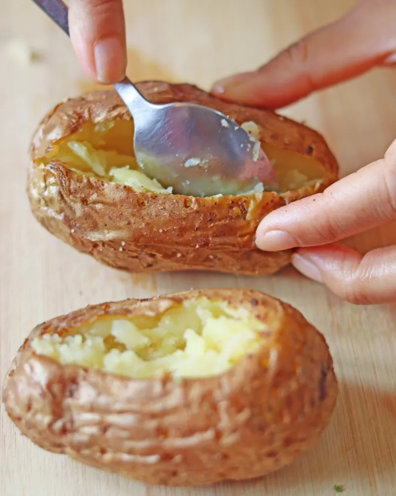 Fluffing the inside of a split baked potato with a spoon