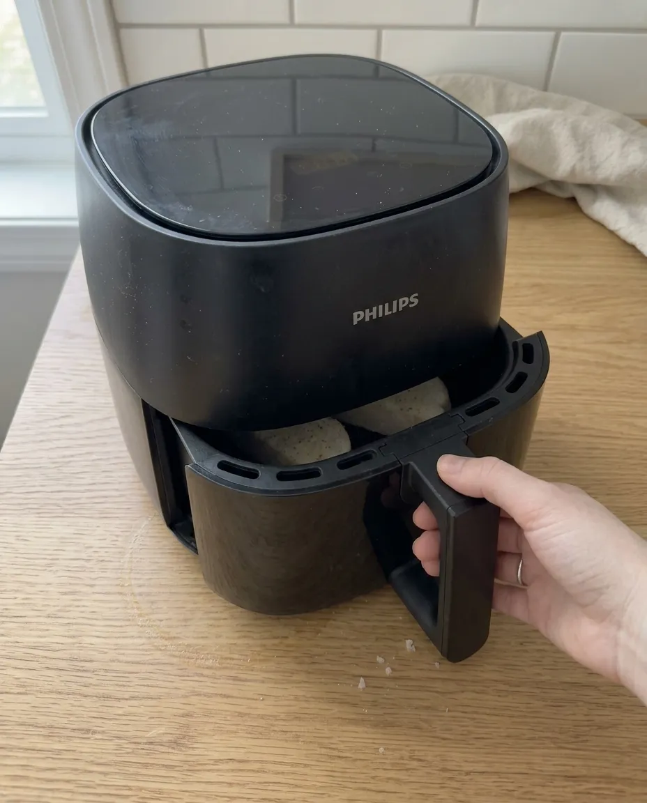 Sliding a basket of frozen garlic bread into the air fryer