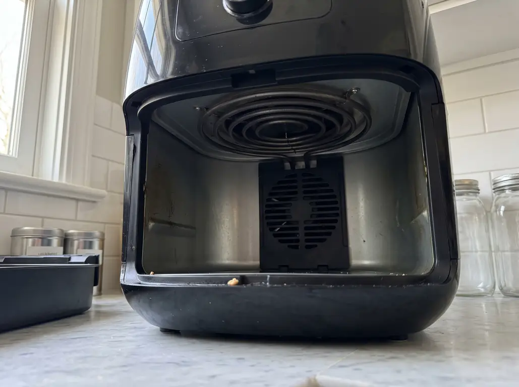 The open cavity of an air fryer with the drawer removed, showing the coiled heating element in the ceiling