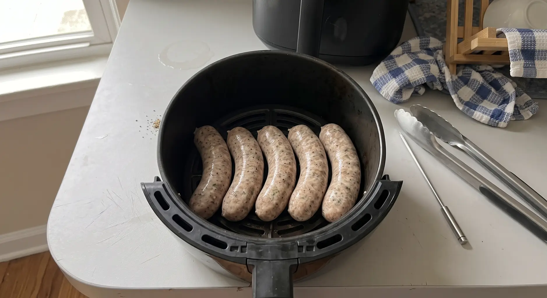 Raw Italian sausage links laid in a single spaced layer in an air fryer basket