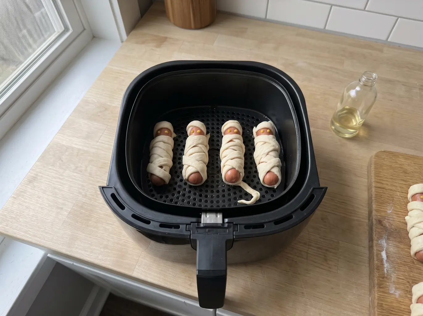 Wrapped mummy dogs arranged in the air fryer basket