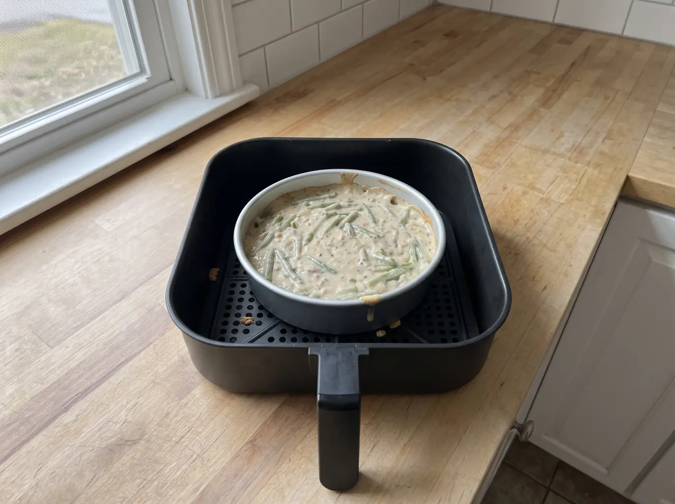 Green bean casserole baking in a pan inside the air fryer basket