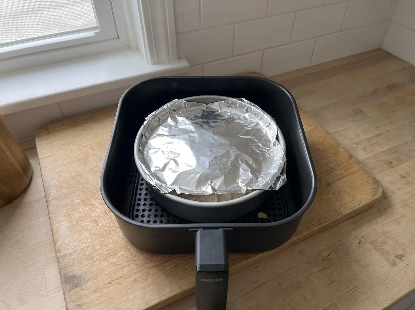 Foil-covered scalloped potatoes in the air fryer basket