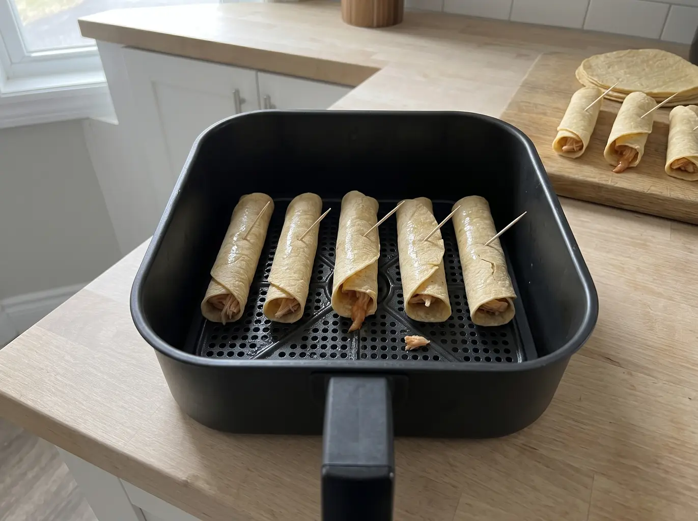 Frozen taquitos seam side down in the air fryer basket